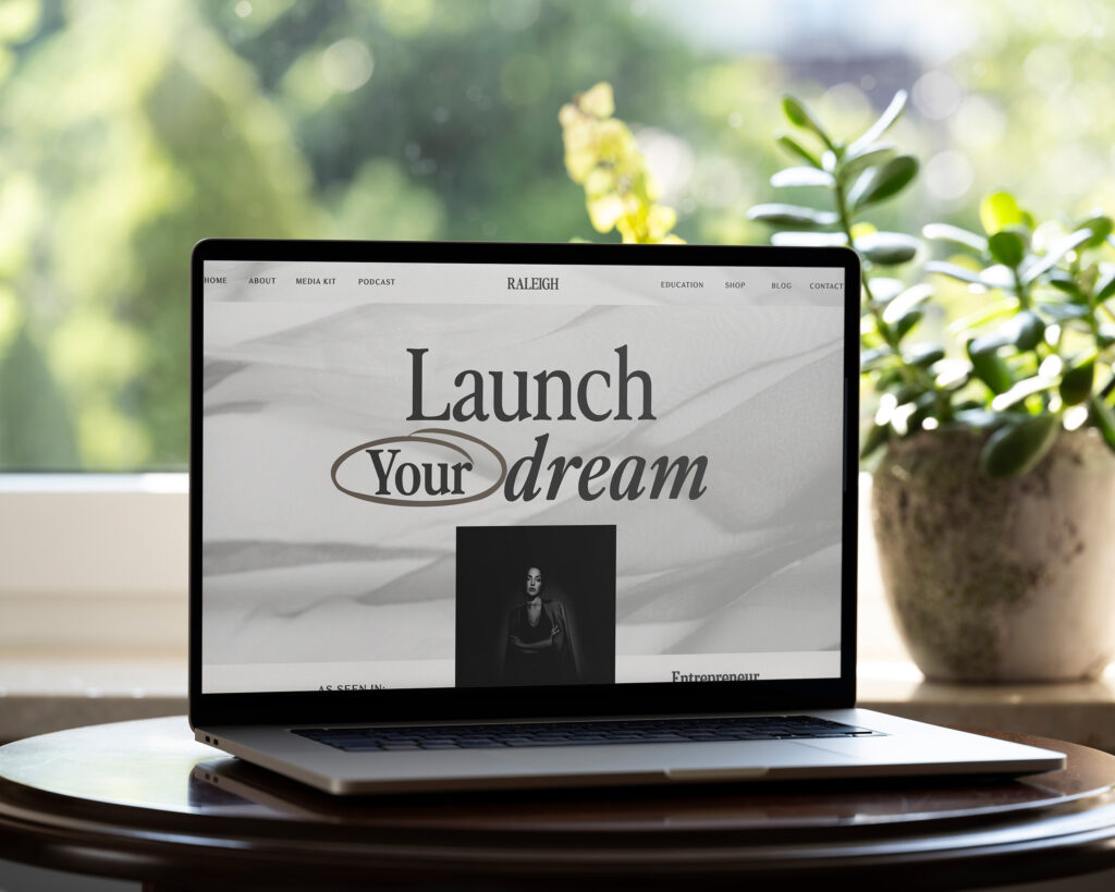 A website by lily is on the screen of a silver laptop sitting on a desk in front of a window.