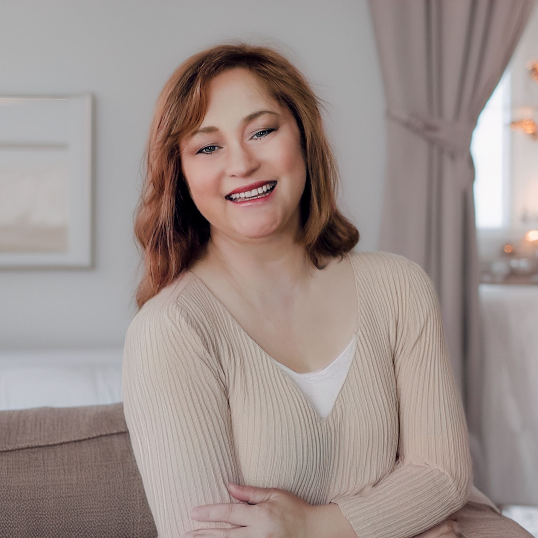 Beth Sheridan, the face behind the Lily brand stands with folded arms, wearing a cream sweater in a neutral toned office.